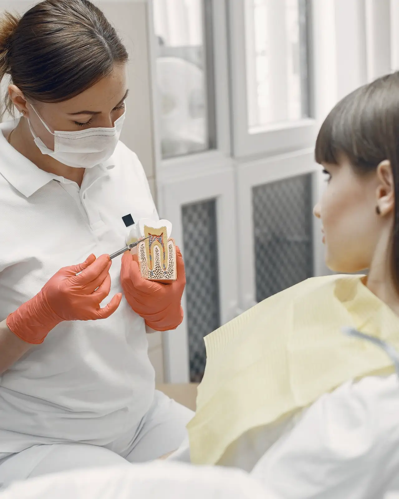 A dentist in gloves talking with a patient in the treatment chair