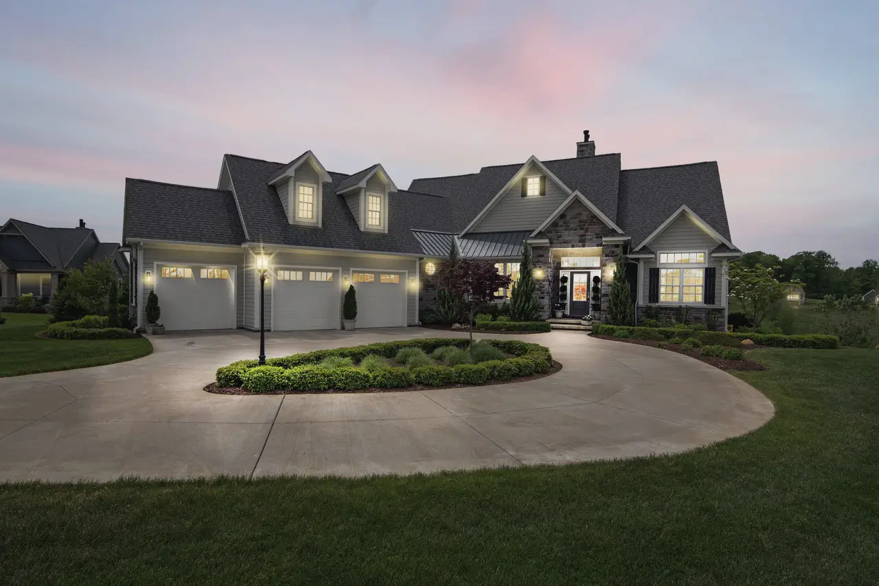 A large two-storey home at dusk with lit windows and a circular driveway