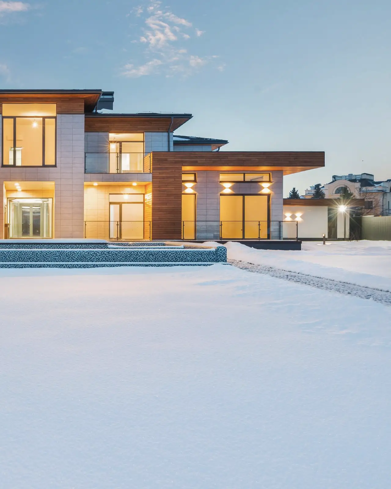 A modern villa with panoramic windows lit up on a winter evening